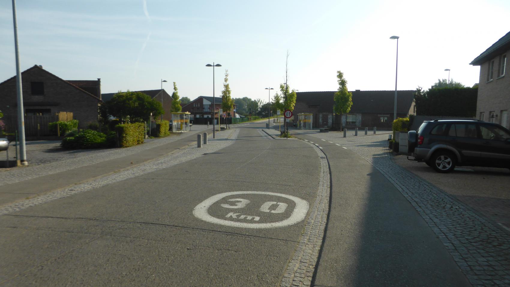 Bus stop Kerkstraat on Lodewijk van Veltemstraat in Beisem. Carriageway narrowed to one lane to provide extra space for passengers entering or leaving the bus without interrupting the cycle traffic.