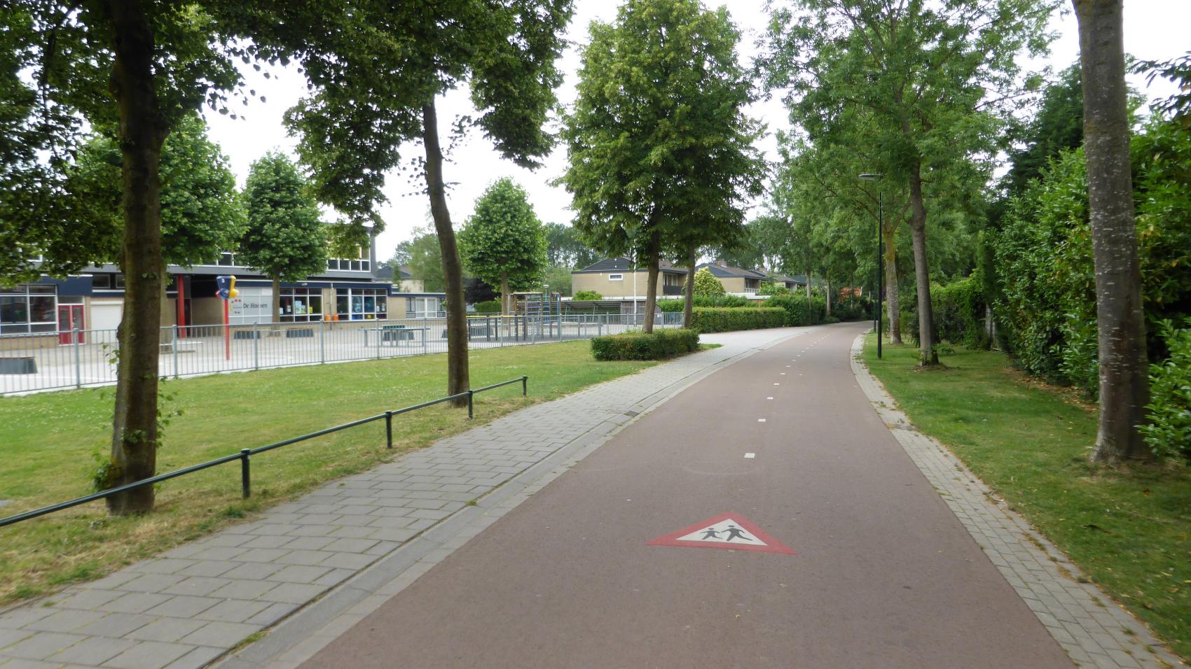 Until eighties this green corridor used to be a car road connecting Beuningen with Nijmegen. Now kids can travel to the catholic elementary school De Hoeven (left side of the picture) by bicycle without being endangered by car traffic.